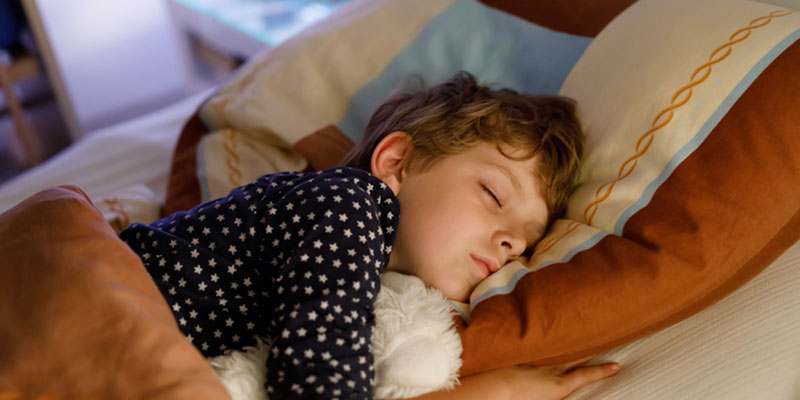 Child sleeping in bed with sleep apnea treatment.